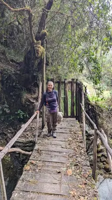 a woman walking on a wooden bridge at EcoLodge Mayu Camping in Cusco