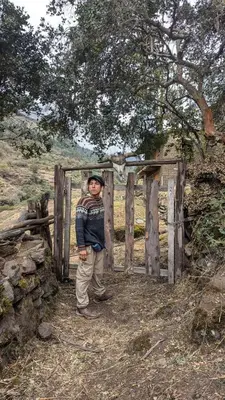 a young boy standing in front of a wooden gate at EcoLodge Mayu Camping in Cusco