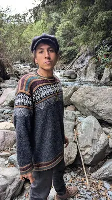 a young boy in a sweater standing on rocks at EcoLodge Mayu Camping in Tanca