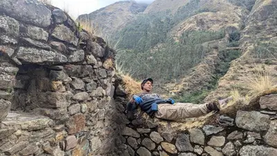 a man laying on the side of a stone wall at EcoLodge Mayu Camping in Tanca
