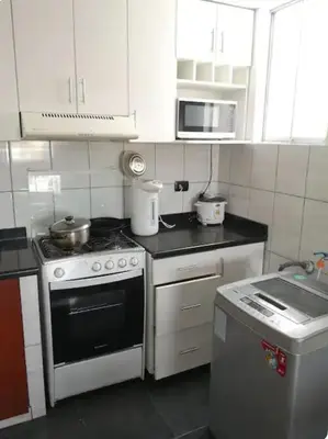 a small kitchen with a stove and a microwave at Edificio La Católica in Lima