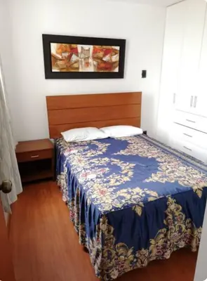 a bedroom with a bed with a blue comforter at Edificio La Católica in Lima