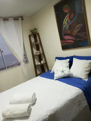 a bedroom with a bed with blue sheets and a window at Habitación con vista al mar in Lima