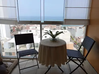 a table and chairs in a room with a large window at Habitación con vista al mar in Lima
