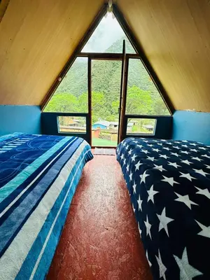 a bed in a room with a large window at Salkantay Lodge Collpapampa in Colcapampa