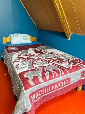 a bed in a room with a blanket on it at Salkantay Lodge Collpapampa in Colcapampa