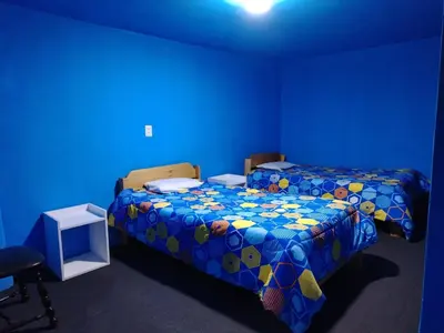 a blue room with two beds and a blue wall at CASa HOSPEDAJE RODRÍGUEZ in Urubamba
