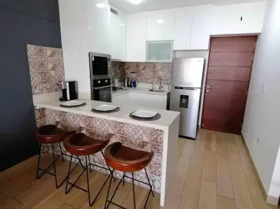 a kitchen with a counter with stools and a refrigerator at Barranco-Miraflores, ubicación A1, hermosa vista in Lima
