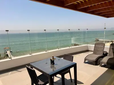 a table and chairs on a balcony with a view of the ocean at Suite 1ra Fila Vista Bahía Paracas - Sotavento 601 T3 in Paracas