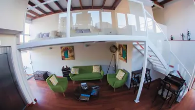 a living room with a staircase and green chairs at Atrium Miraflores Hotel in Lima