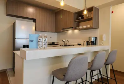 a kitchen with a counter with three chairs and a counter top at Treehouse by Wynwood house in Lima