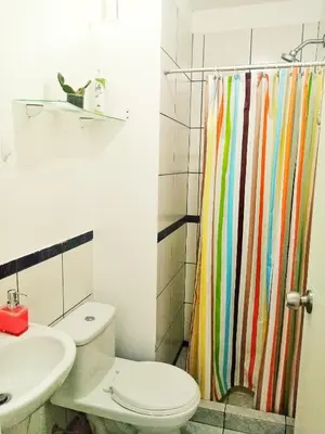 a bathroom with a toilet and a rainbow shower curtain at Departamento Lima acogedor, ventilado, cálido y moderno San miguel, Lima, Perú in Lima