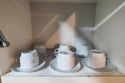 a shelf with four cups and saucers on it at Casa de 4 pisos cerca a embajada de USA y centros comerciales in Lima