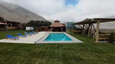 a swimming pool with chairs and a gazebo at Taypu bungalow in Lunahuaná