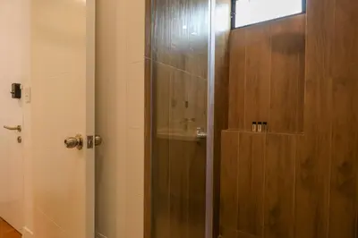 a shower with a glass door in a bathroom at Pendragon by Wynwood House in Lima