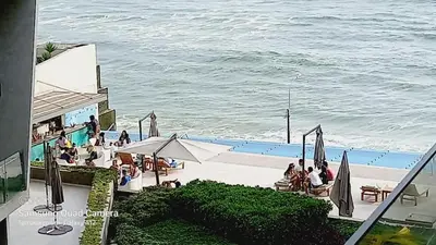 a group of people sitting around a pool next to the ocean at Departamento en PLAYA San Bartolo in San Bartolo