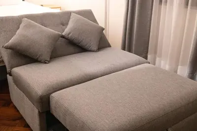 a gray couch with two pillows on top of it at Modern loft in front of the boardwalk and the sea in Lima