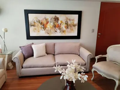 a living room with a couch and a painting on the wall at El Libertador Apartment Miraflores in Lima