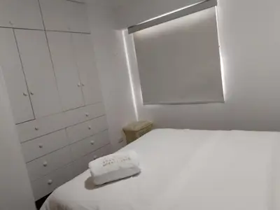 a white bedroom with a bed and a window at El Libertador Apartment Miraflores in Lima
