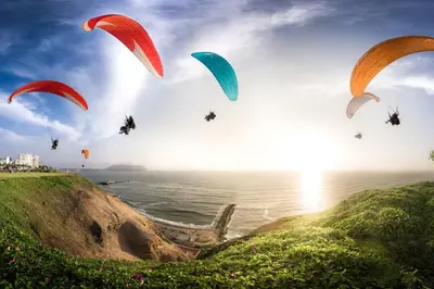 a group of people riding parachutes over the ocean at Private room by the sea Miraflores in Lima