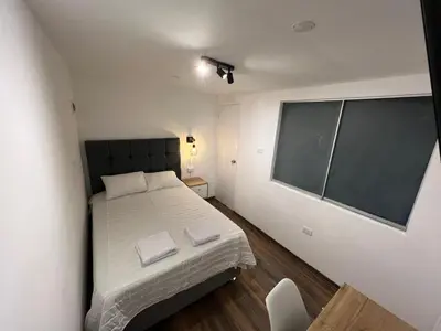 a small bedroom with a bed and a large window at Modern Duplex by the sea Miraflores in Lima