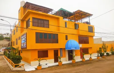 a yellow building with plants in front of it at Hostal Ocean Pacifico in Punta Negra