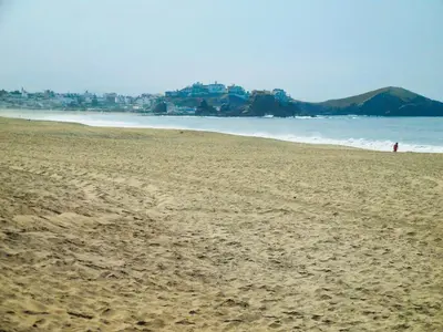 a person walking on a sandy beach near the ocean at Hostal Ocean Pacifico in Punta Negra
