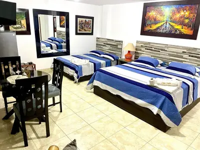 a bedroom with three beds and a table and a desk at Hostal Ocean Pacifico in Punta Negra