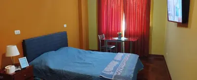 a bedroom with a bed and a table and a window at Habitación H2, TV y WIFI cerca a Barranco in Lima