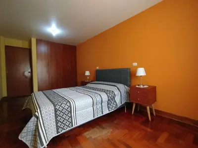 a bedroom with a bed and a wooden floor at Habitación H2, TV y WIFI cerca a Barranco in Lima