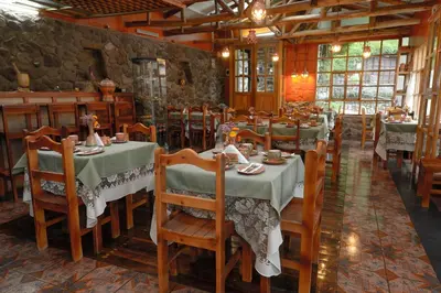 a restaurant with tables and chairs in a room at Hotel Samanapaq in Ollantaytambo