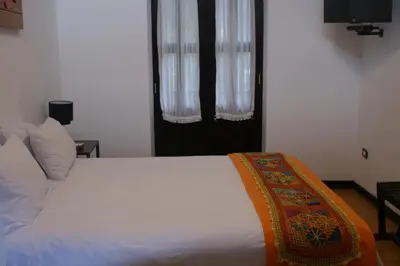 a bedroom with a white bed and two windows at Hotel Samanapaq in Ollantaytambo