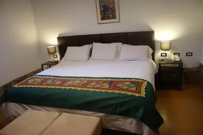 a bedroom with a large bed with two tables at Hotel Samanapaq in Ollantaytambo
