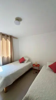 two beds in a room with a table and a window at loft apartament residencial ICA in Ica