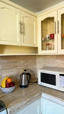 a kitchen counter with a microwave and a bowl of fruit at Loft Huacachina center ica in Ica