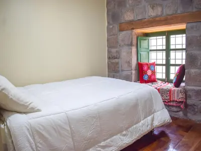 a bedroom with a white bed and a window at Acogedor Departamento en Barrio Resbalosa, a 5 Min de la Plaza de Cusco in Cusco
