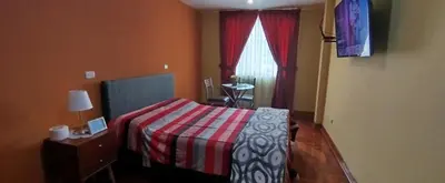 a bedroom with a bed with a red and white blanket at Habitación H3, TV y WIFI cerca a Barranco in Lima