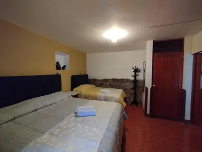 a hotel room with two beds and a red door at La Casa de Abril Cusco in Cusco