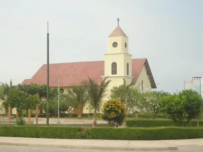 a church with a clock tower in front of a building at Blue Shark Apartments in San Bartolo