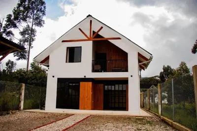 a small white building with a balcony on top of it at La Casa de Anni Departamento 2 in Oxapampa