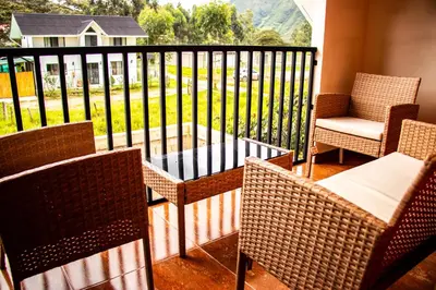 a balcony with wicker chairs and a table and a table and chairs at La Casa de Anni Departamento 2 in Oxapampa