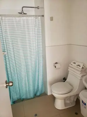 a bathroom with a toilet and a blue shower curtain at Amplio, Bonito , Silencioso y céntrico en Miraflores in Lima