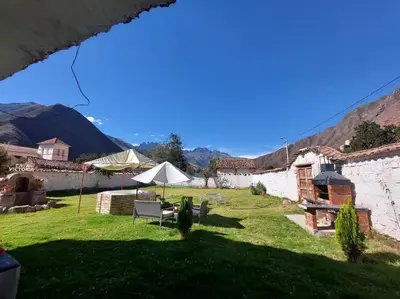a garden with a table and an umbrella in a yard at Casa Victoria - Huayllabamba, Urubamba Cusco, Perú in Huayllabamba