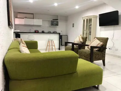 a living room with a green couch and two chairs at Departamento en corazón de Miraflores in Lima