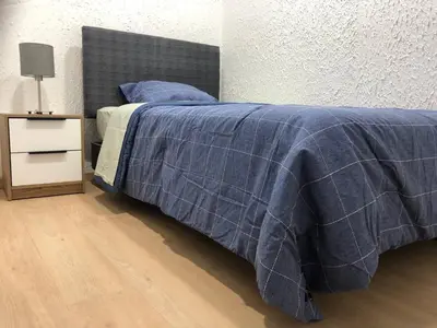 a bed with a blue blanket and a night stand at Departamento en corazón de Miraflores in Lima