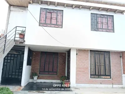 a white building with black doors and windows at Casita de camucha in Chincha Baja