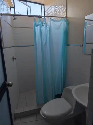 a bathroom with a toilet and a blue shower curtain at Habitaciones en la Casa de Dora, 4to y 5to piso in Ayacucho