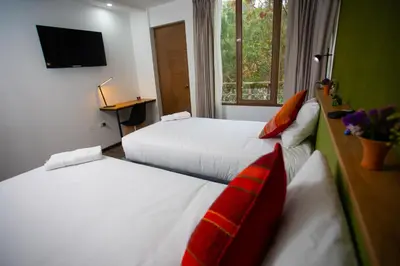 a hotel room with two beds and a television at MUJU hotel by Ämak in Urubamba