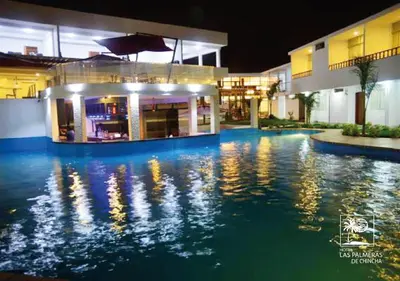 a swimming pool in front of a building at night at Qallwa Chincha in Chincha Alta