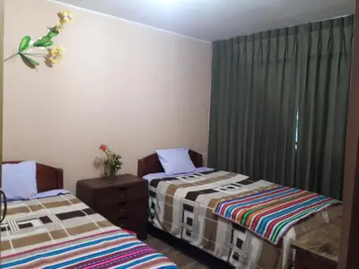 a bedroom with two beds and a dresser and curtains at Hostal El Viajero in Surcubamba
